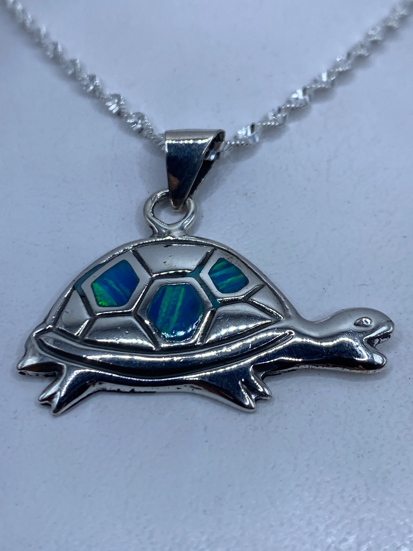 Dije de tortuga en plata .925 con ópalo de fuego azul colgado de cadena plateada