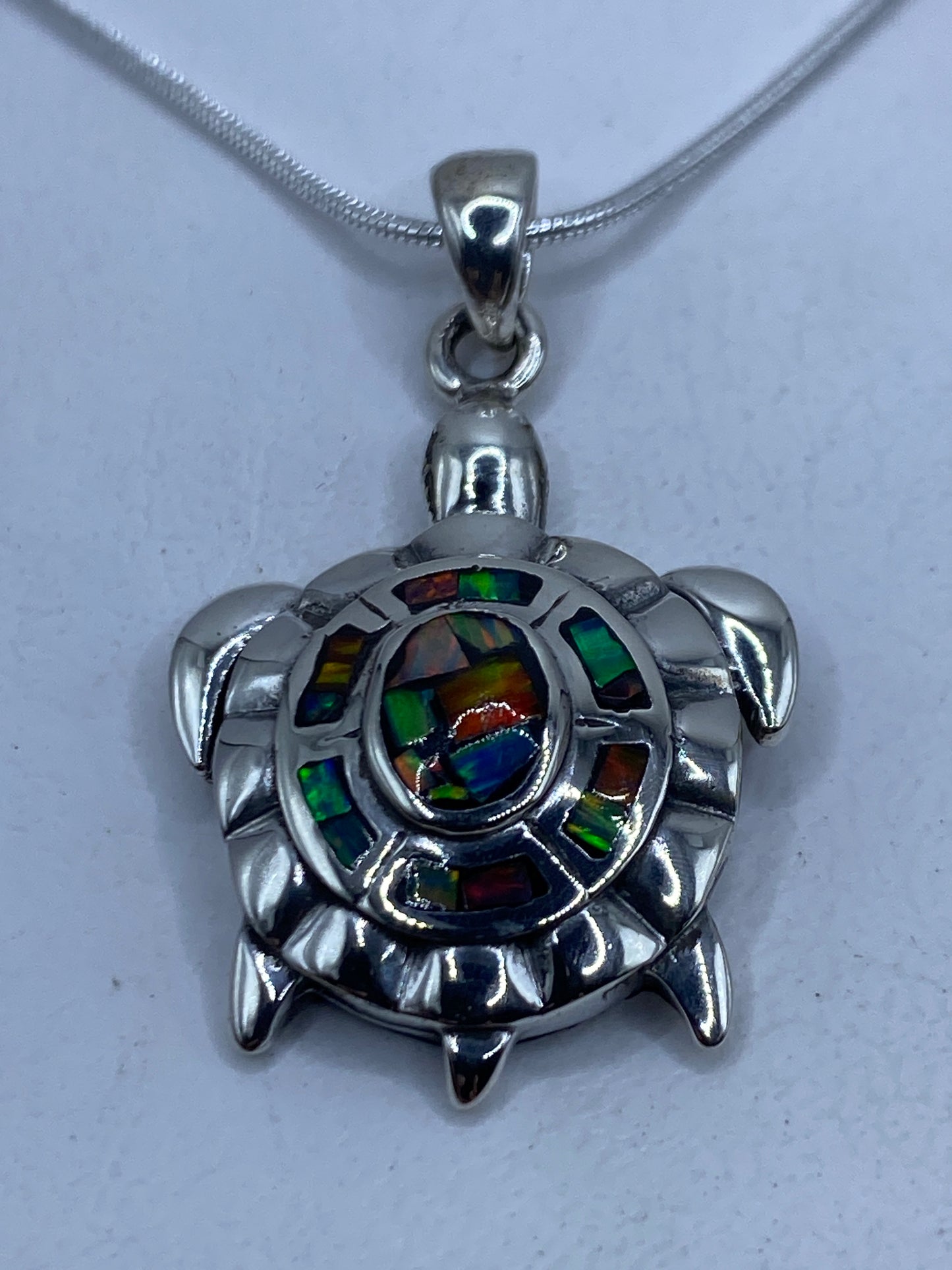 Dije tortuga en plata .950 con ópalo de fuego multicolor colgando de cadena de plata