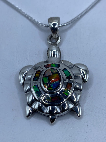 Dije tortuga en plata .950 con ópalo de fuego multicolor colgando de cadena de plata