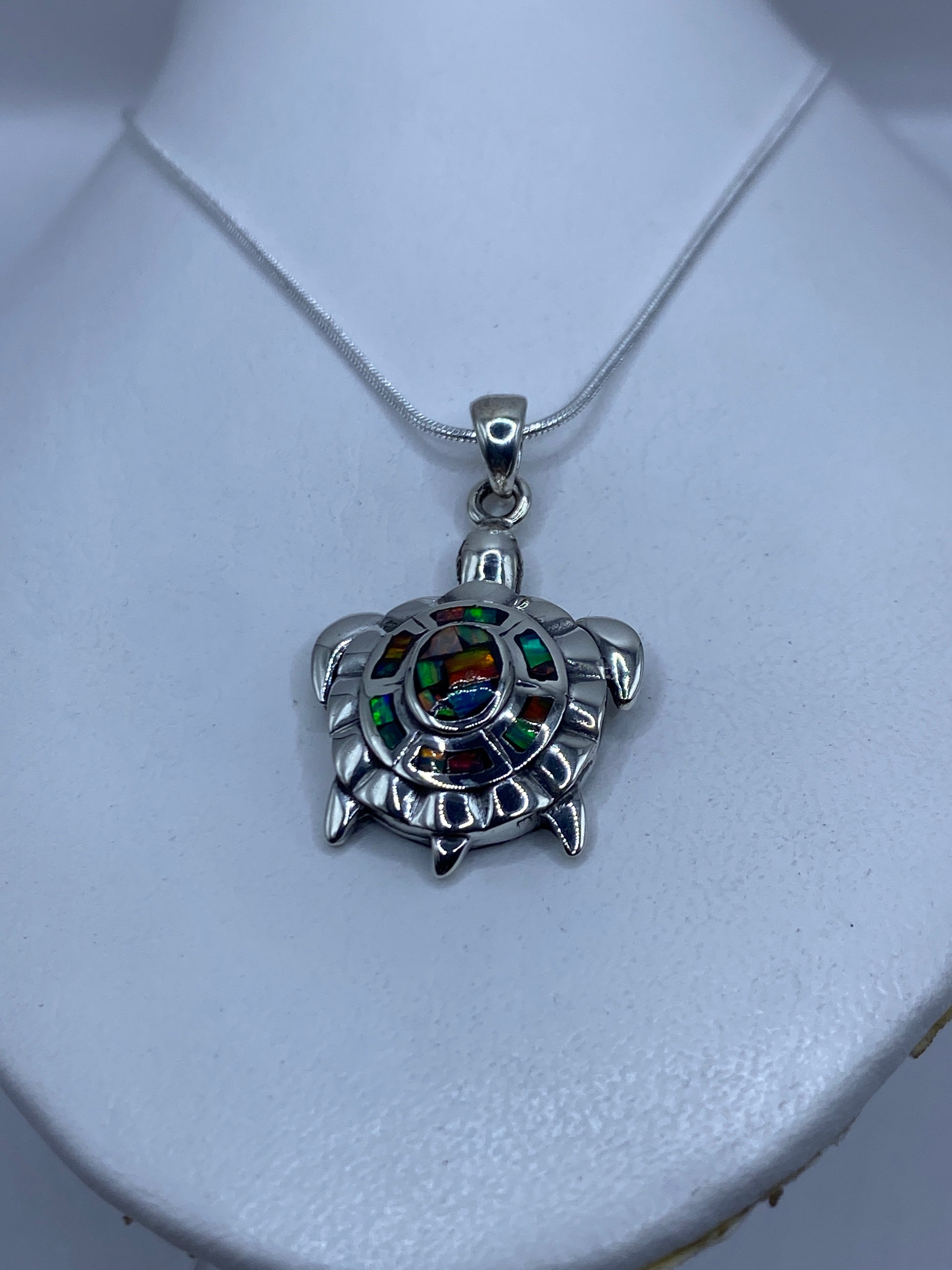 Detalle del dije tortuga mostrando el ópalo de fuego engastado en el caparazón
