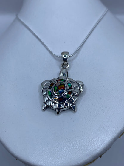 Detalle del dije tortuga mostrando el ópalo de fuego engastado en el caparazón