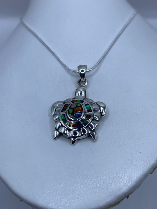 Detalle del dije tortuga mostrando el ópalo de fuego engastado en el caparazón