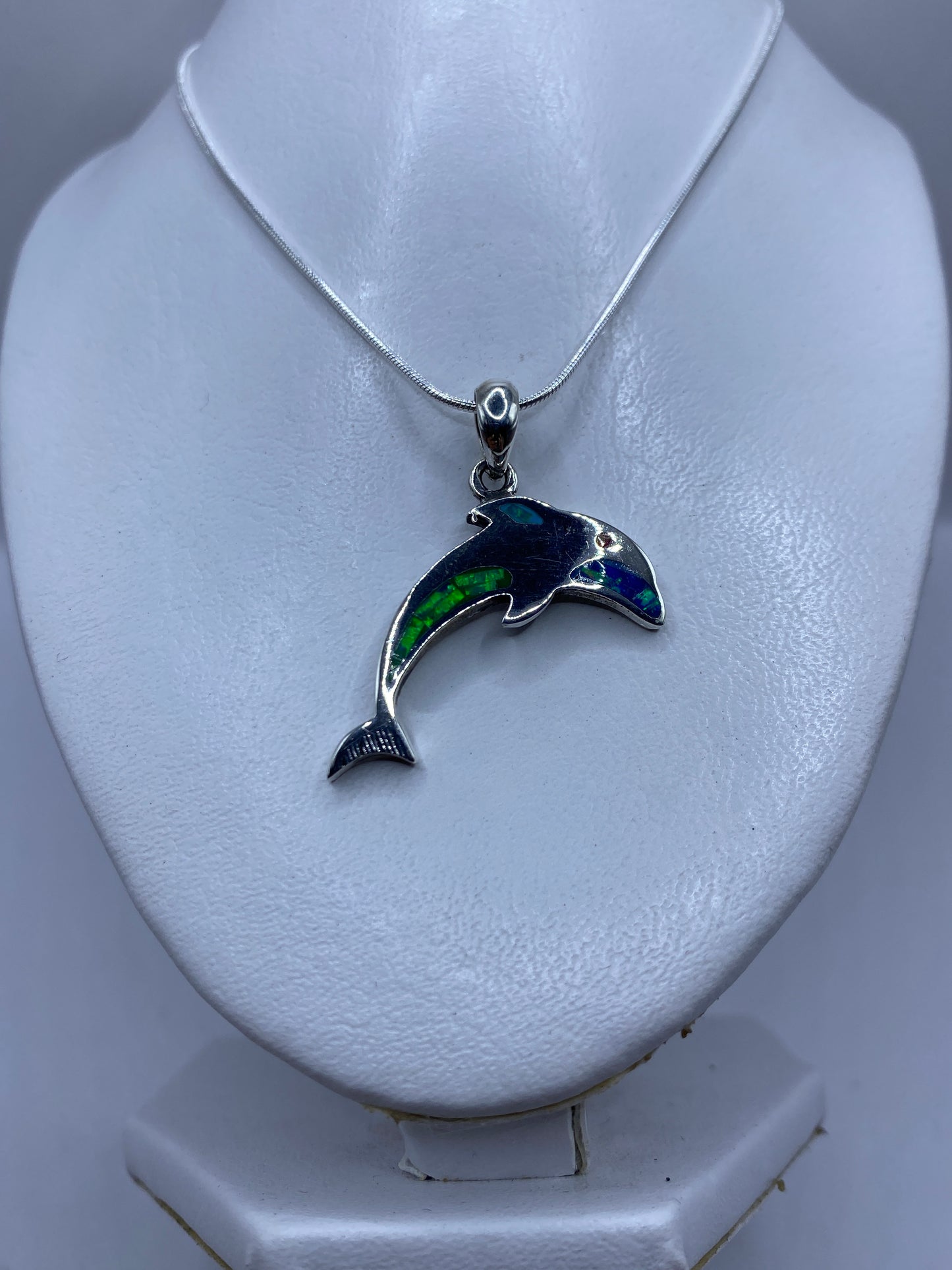 Primer plano del ópalo de fuego multicolor engastado en plata .950, mostrando reflejos verdes y azules