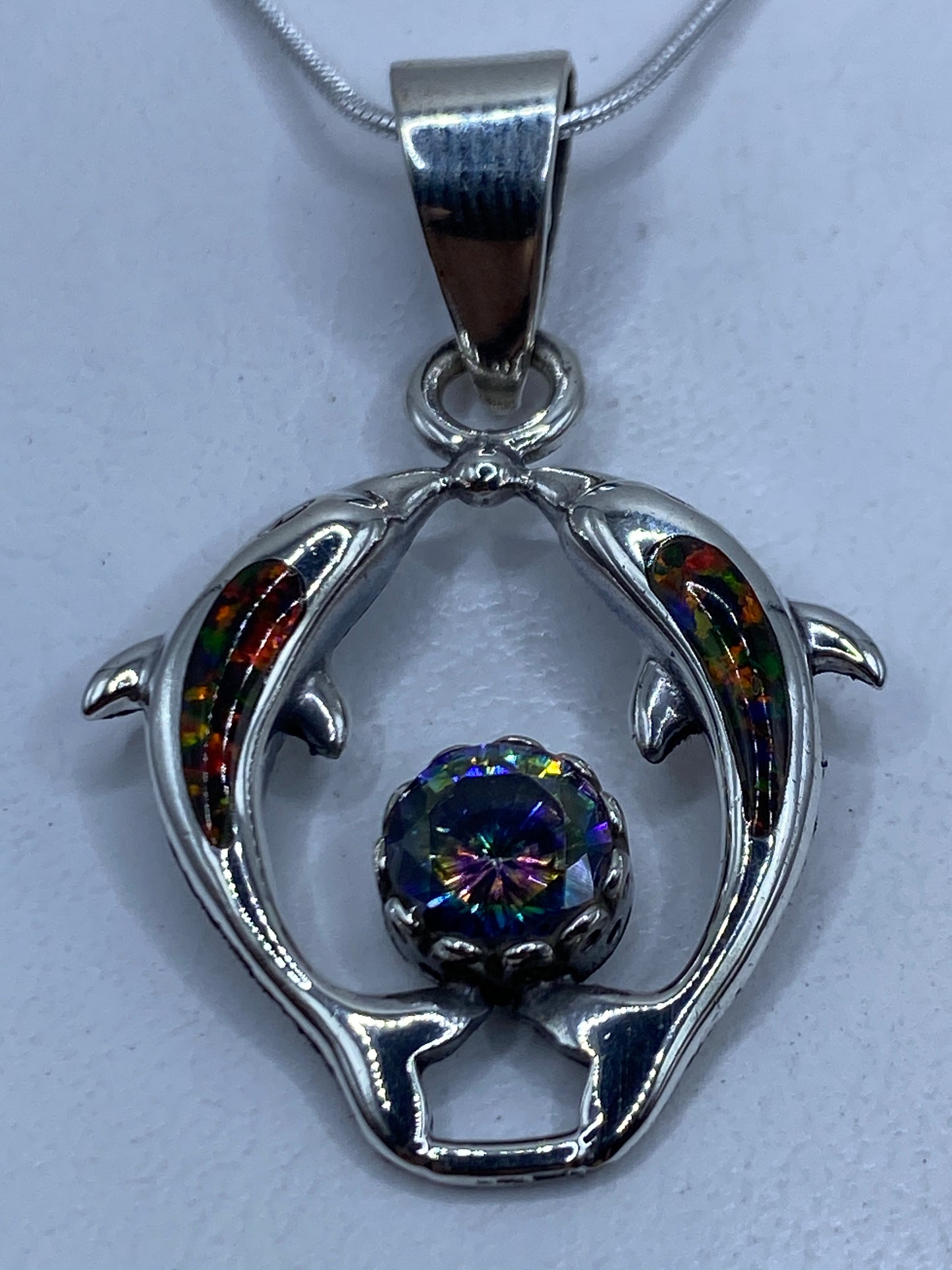 Dije de plata con delfines y ópalo de fuego multicolor colgando de cadena plateada