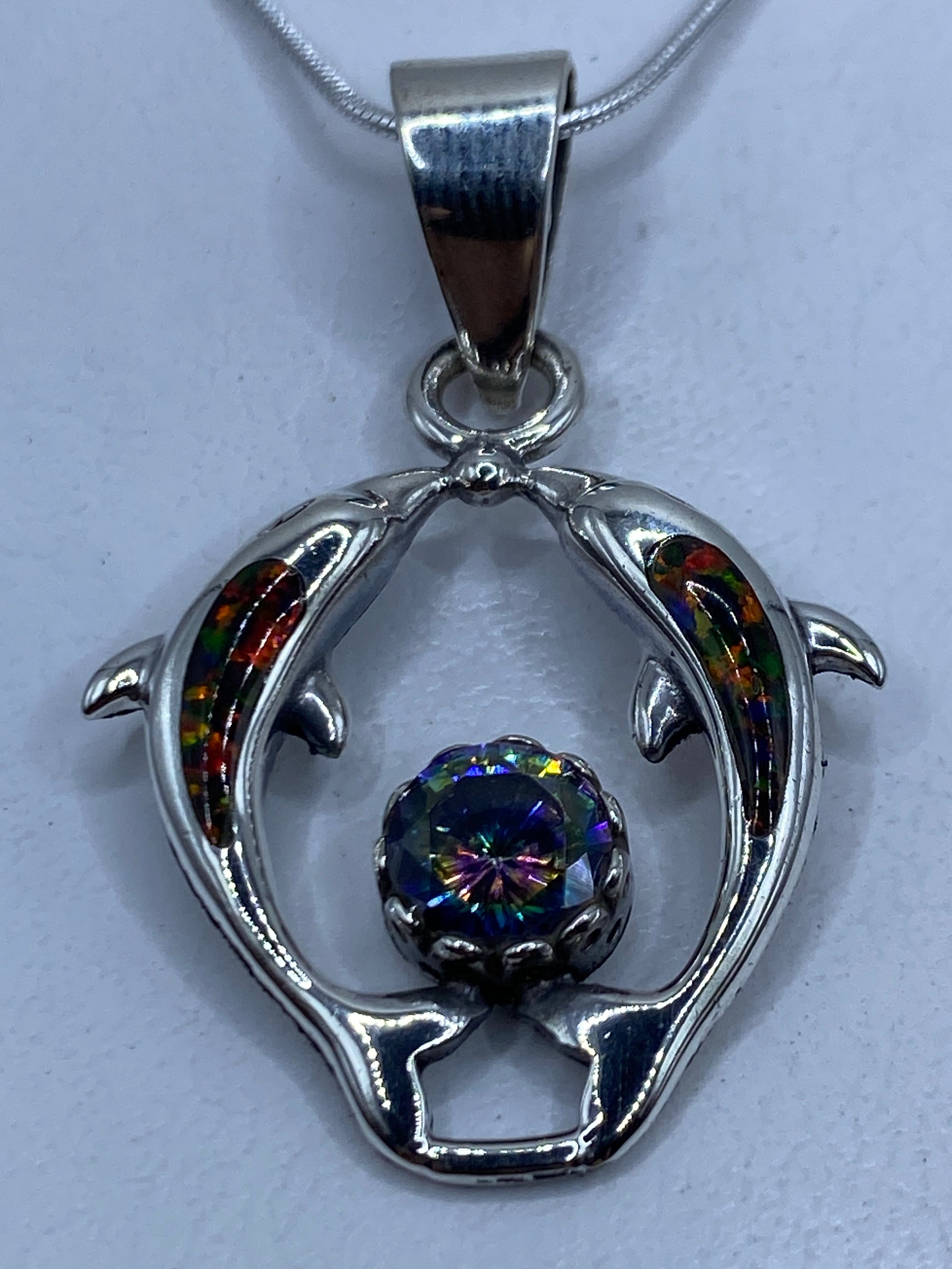 Dije de plata con delfines y ópalo de fuego multicolor colgando de cadena plateada