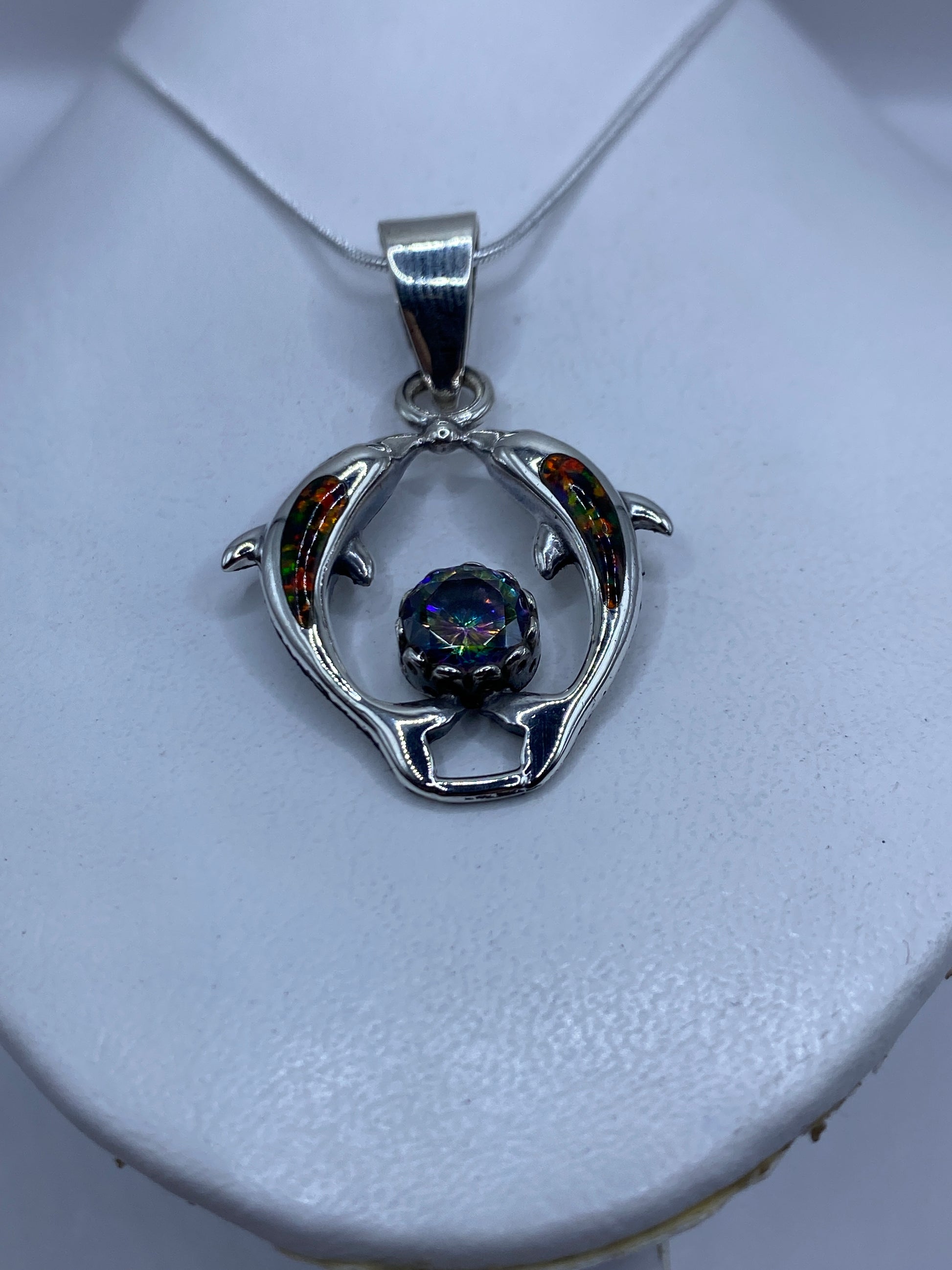 Detalle del ópalo de fuego multicolor engastado entre los delfines de plata
