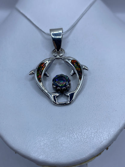 Detalle del ópalo de fuego multicolor engastado entre los delfines de plata