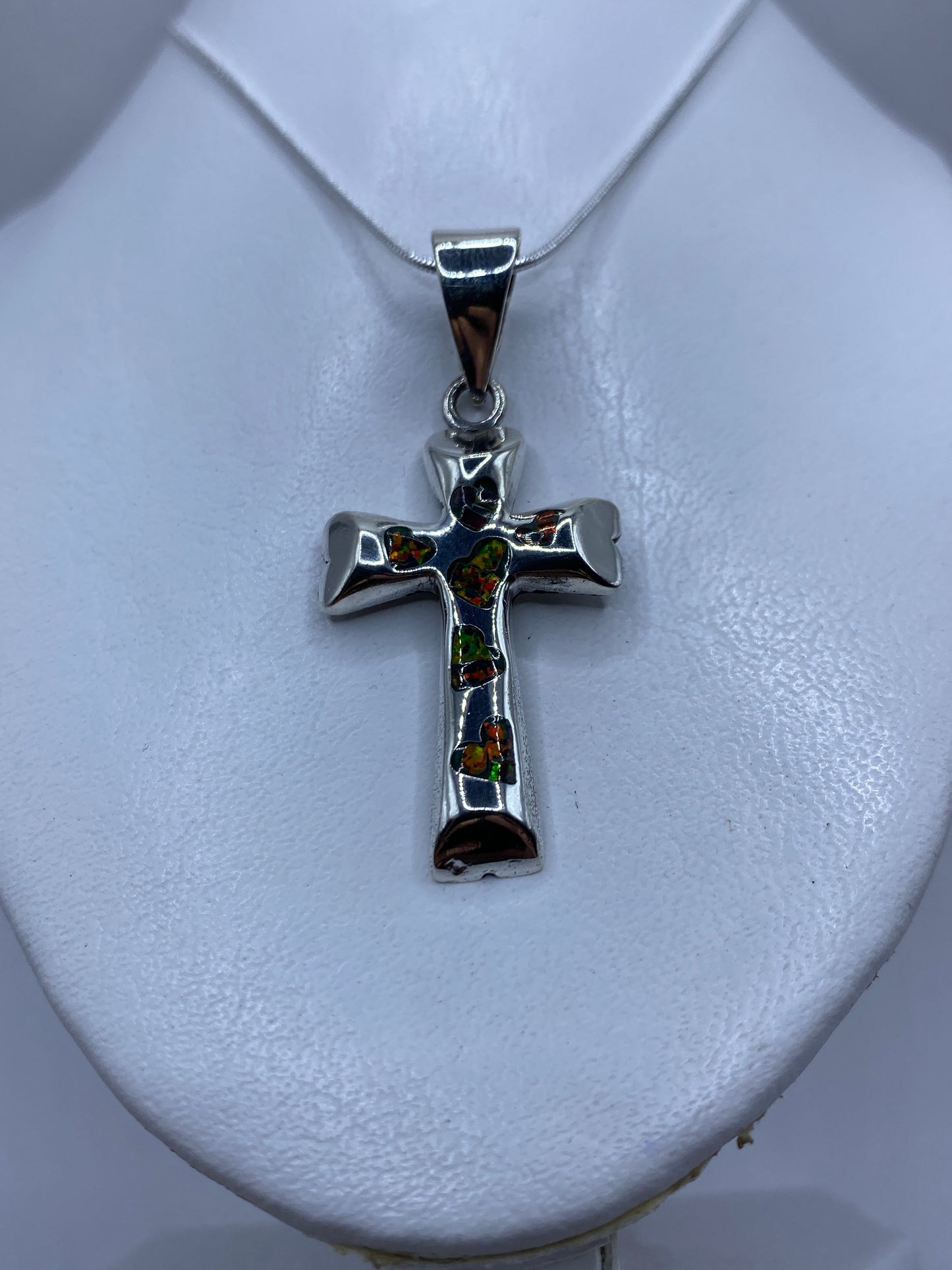 Detalle del ópalo de fuego multicolor y el engaste a mano en la cruz