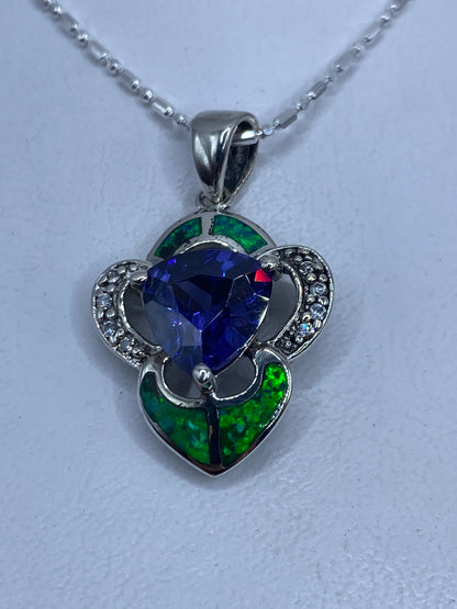 Dije de plata con ópalo de fuego verde y detalles florales en circonia, colgando de cadena delgada