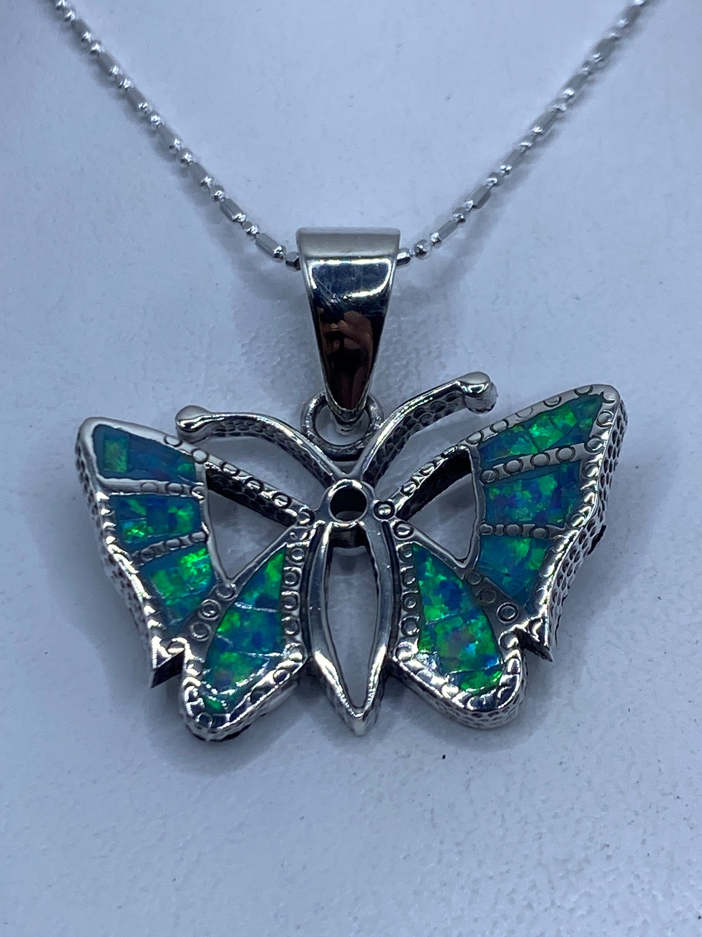 Dije mariposa de plata .950 con ópalo de fuego azul cielo, colgado de cadena plateada