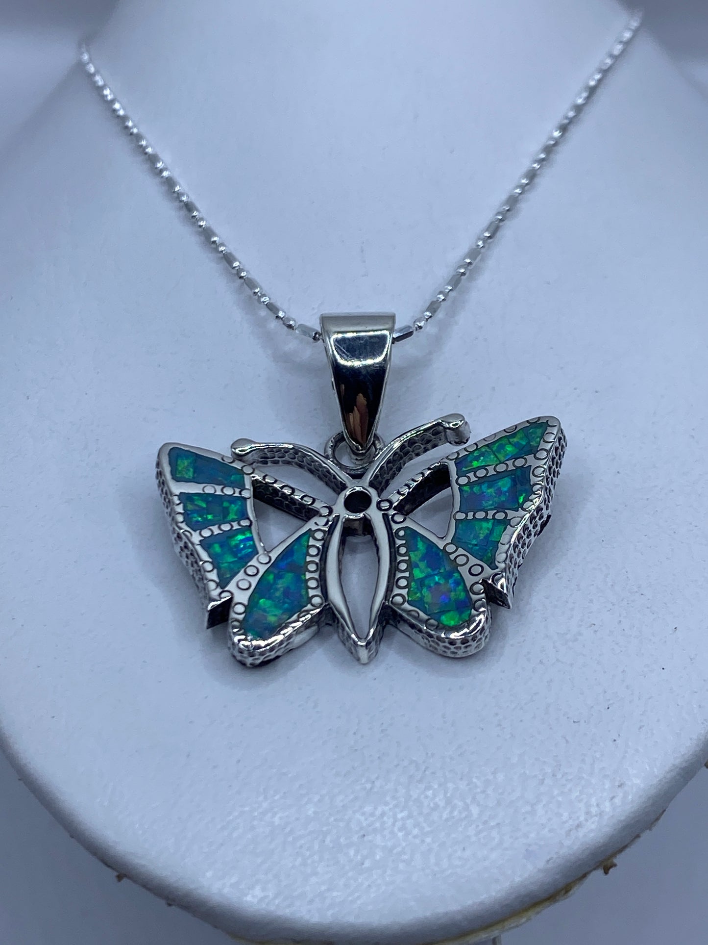 Detalle frontal de la mariposa mostrando la incrustación de ópalo y el granulado de plata