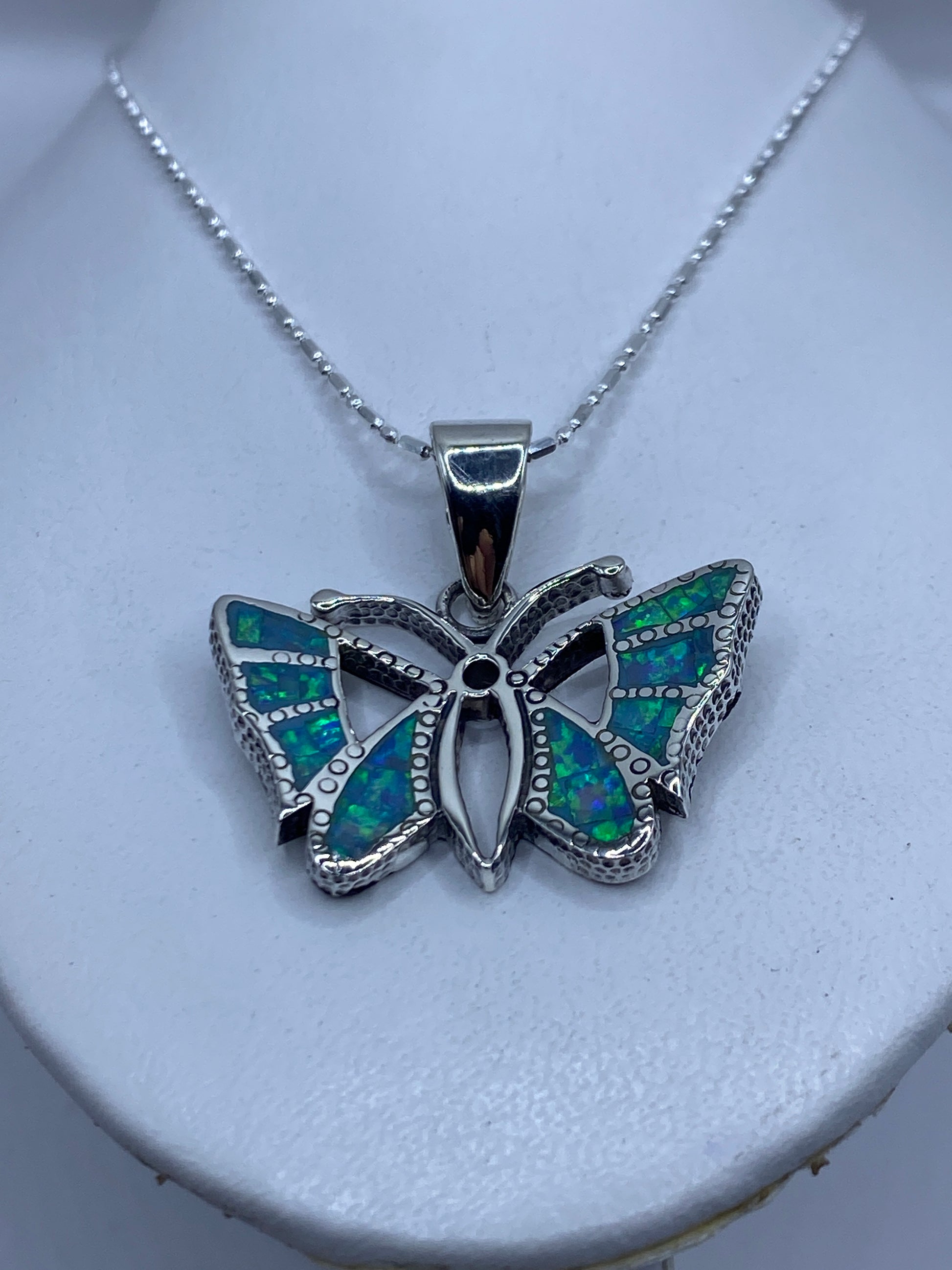 Detalle frontal de la mariposa mostrando la incrustación de ópalo y el granulado de plata