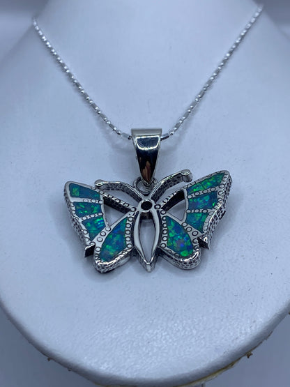Detalle frontal de la mariposa mostrando la incrustación de ópalo y el granulado de plata
