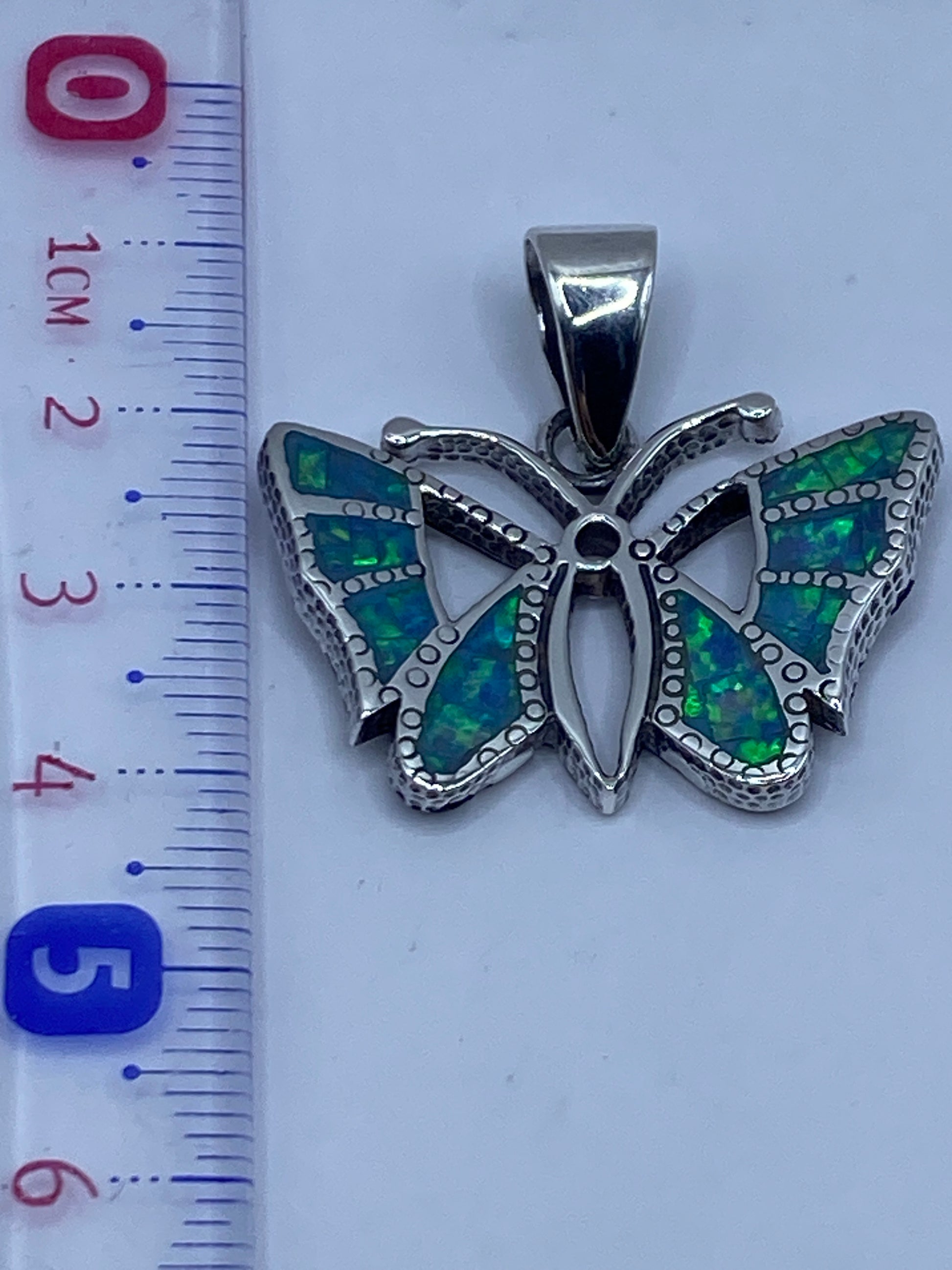 Mariposa de plata junto a regla mostrando tamaño de 4.2 cm