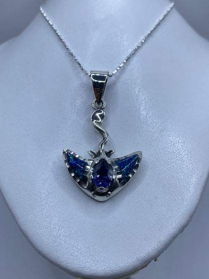 Detalle lateral del dije mostrando el engaste delicado de la piedra azul y las alas de plata