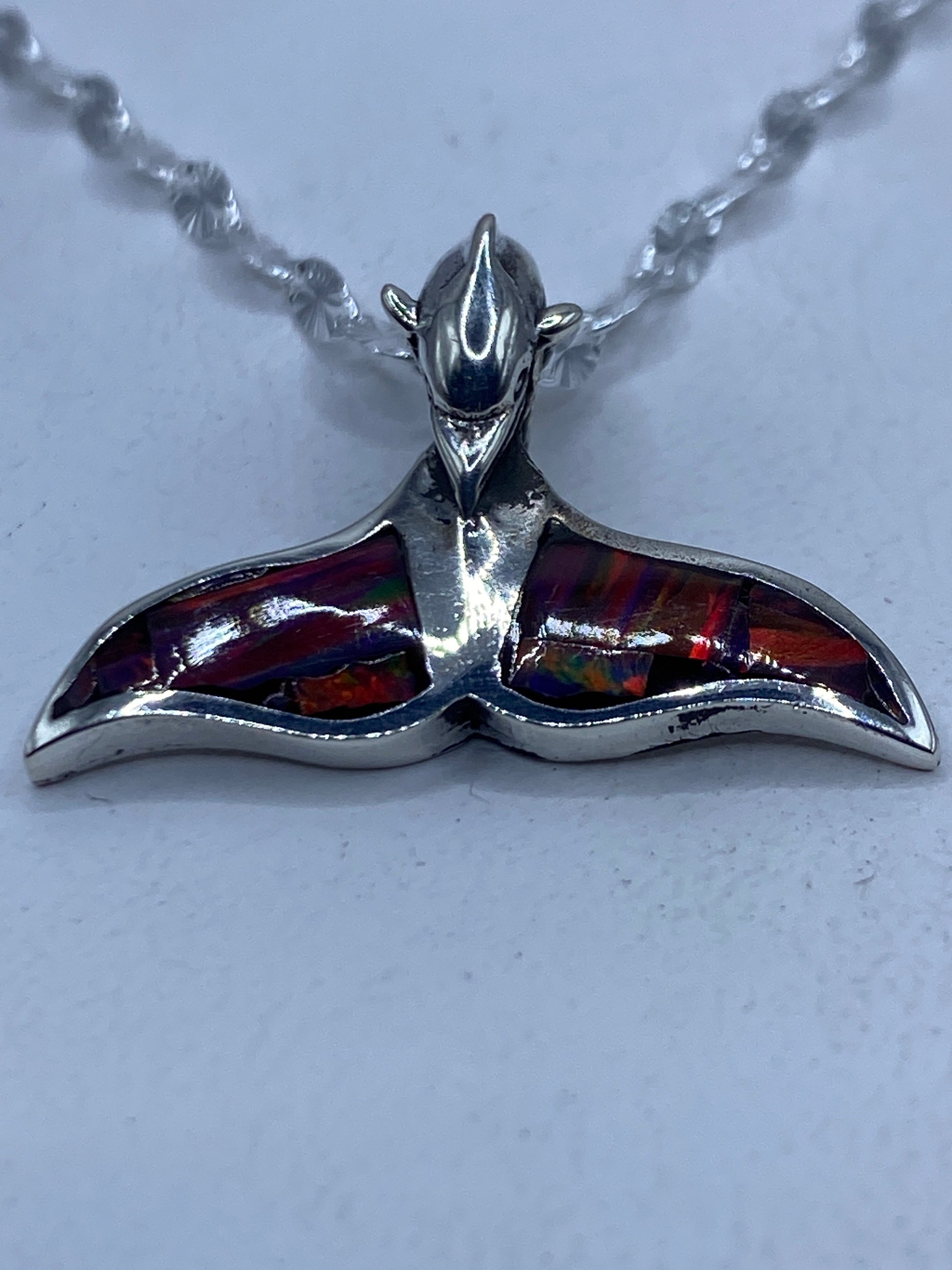 Dije de plata con ópalo de fuego multicolor en forma de cola de ballena, sobre cadena de plata con detalles florales