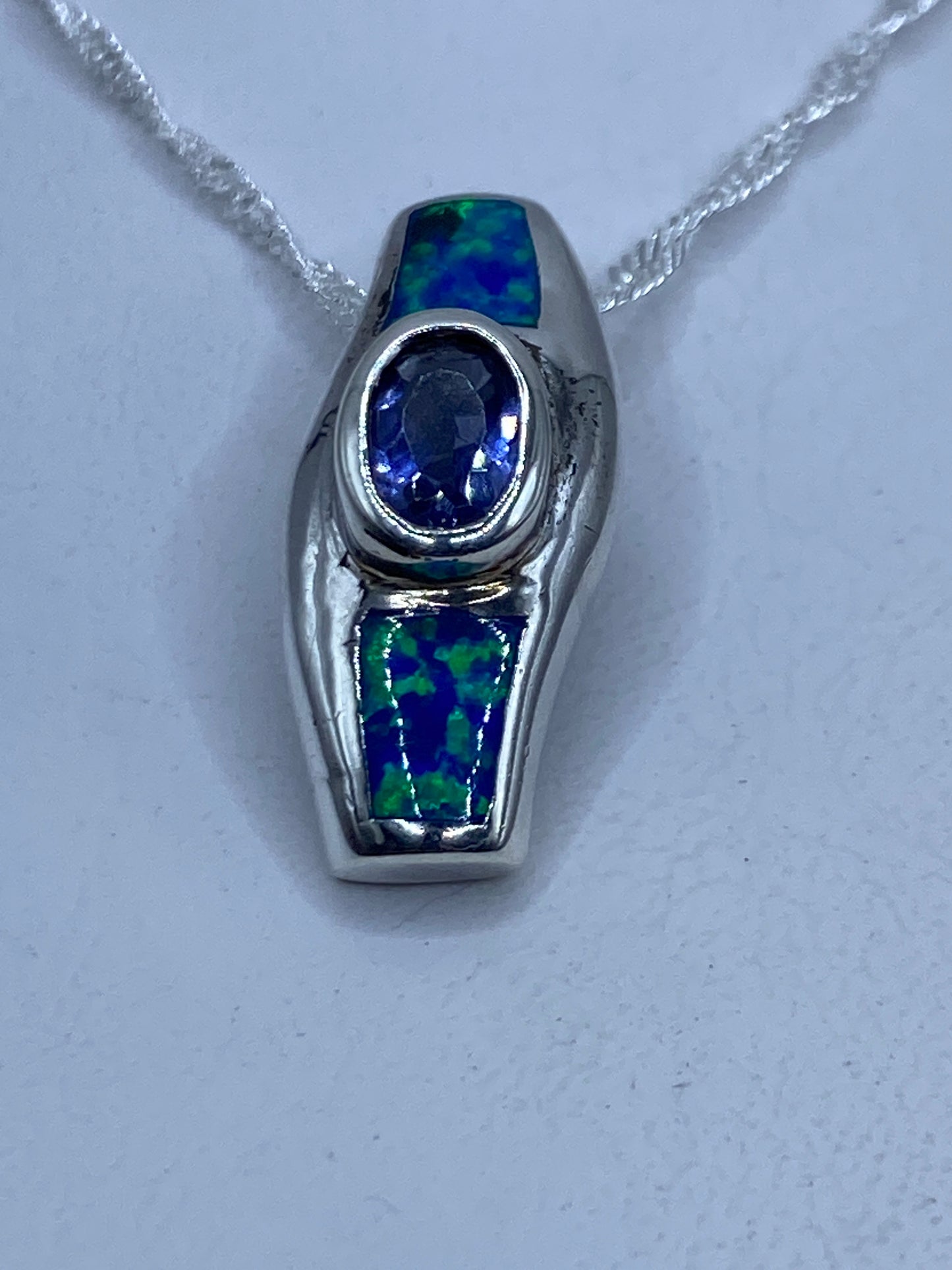 Dije de plata .925 con ópalo de fuego azul engastado, colgando de cadena plateada