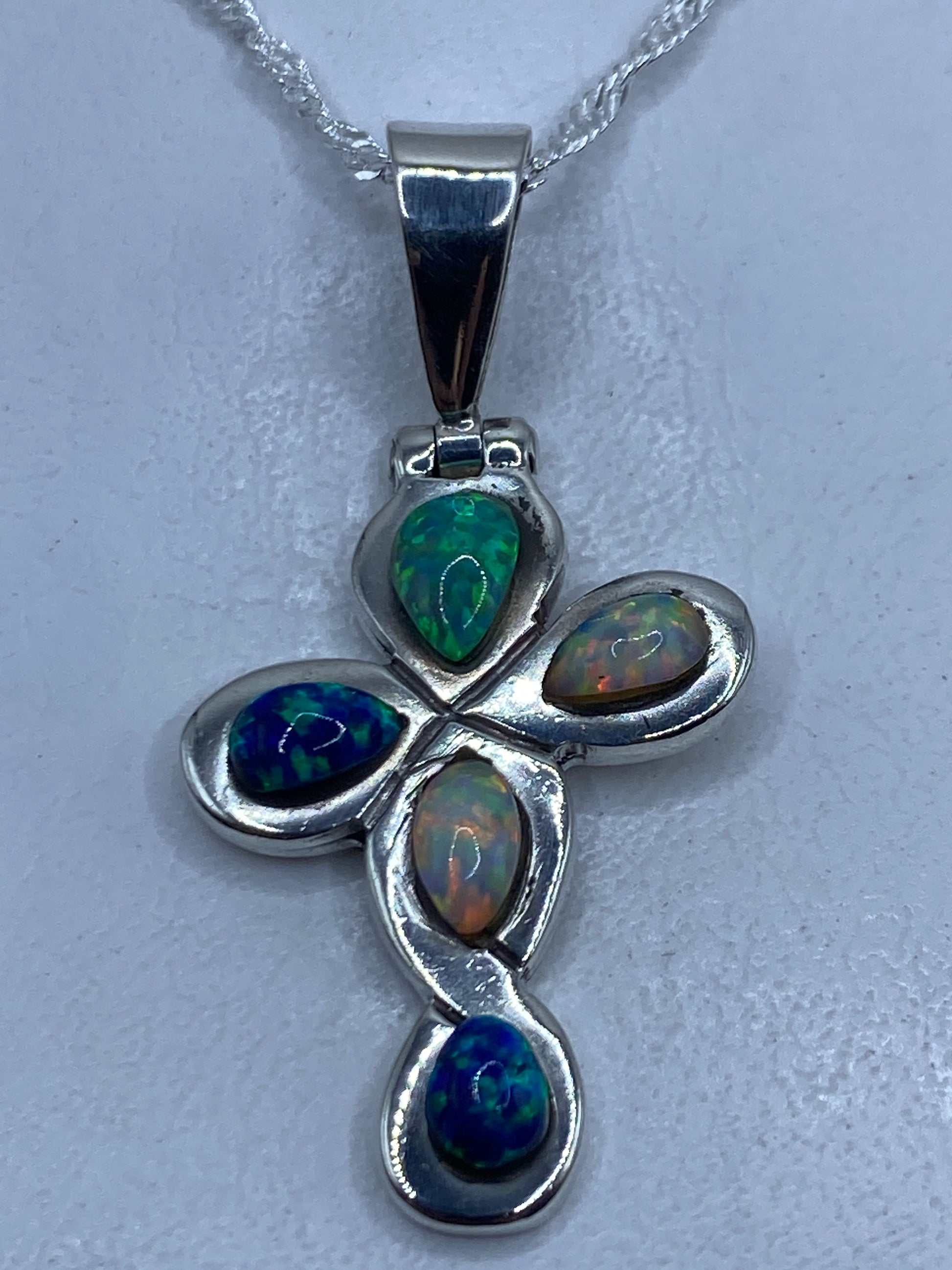Dije cruz de plata .925 con ópalo de fuego multicolor engastado, en cadena plateada