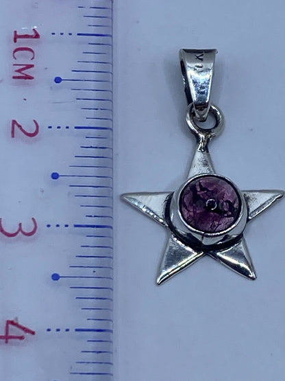Dije de estrella de 3.3 cm sobre regla de medición