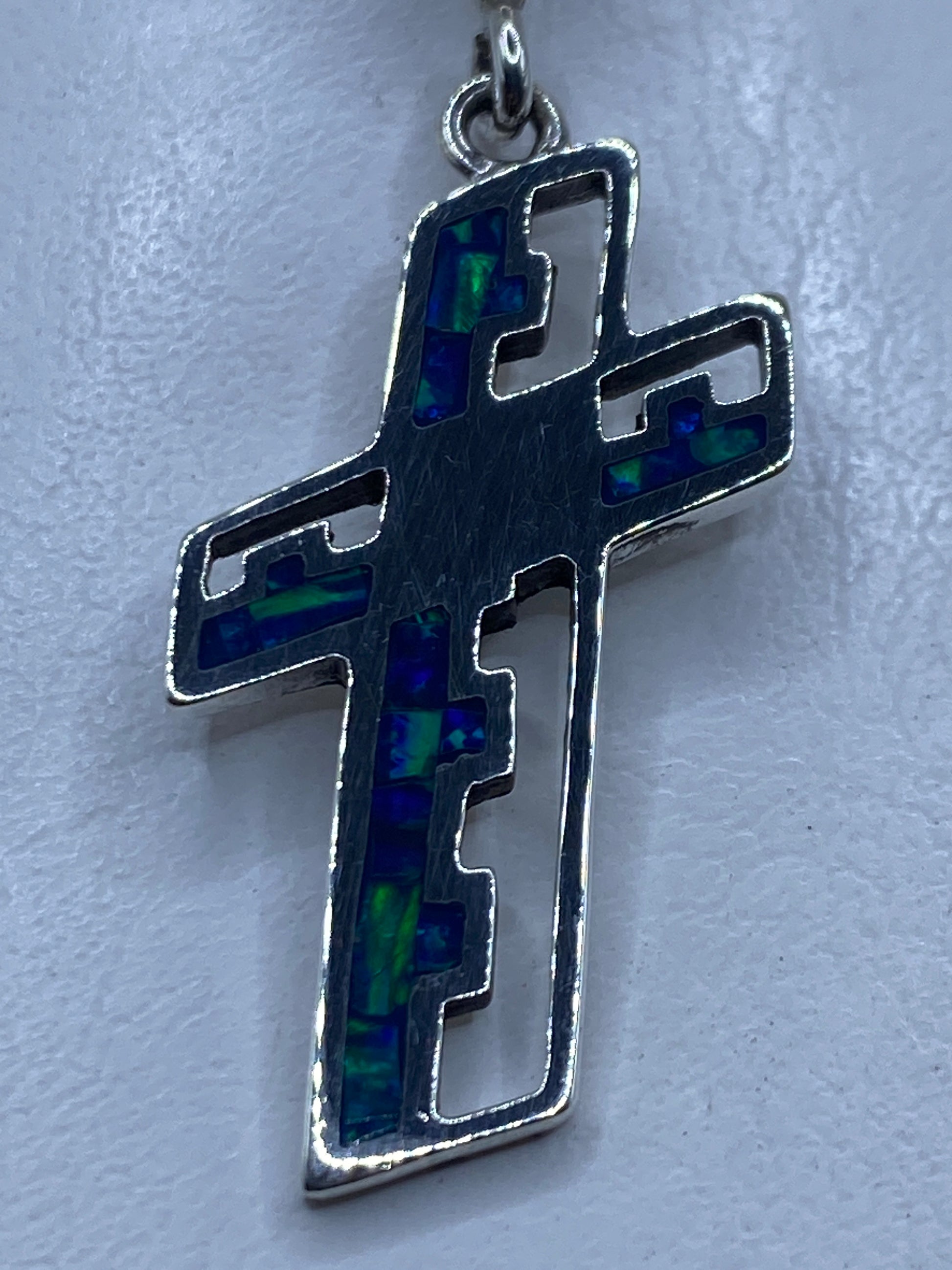 Dije cruz de plata .950 con ópalo de fuego azul, vista frontal detallada