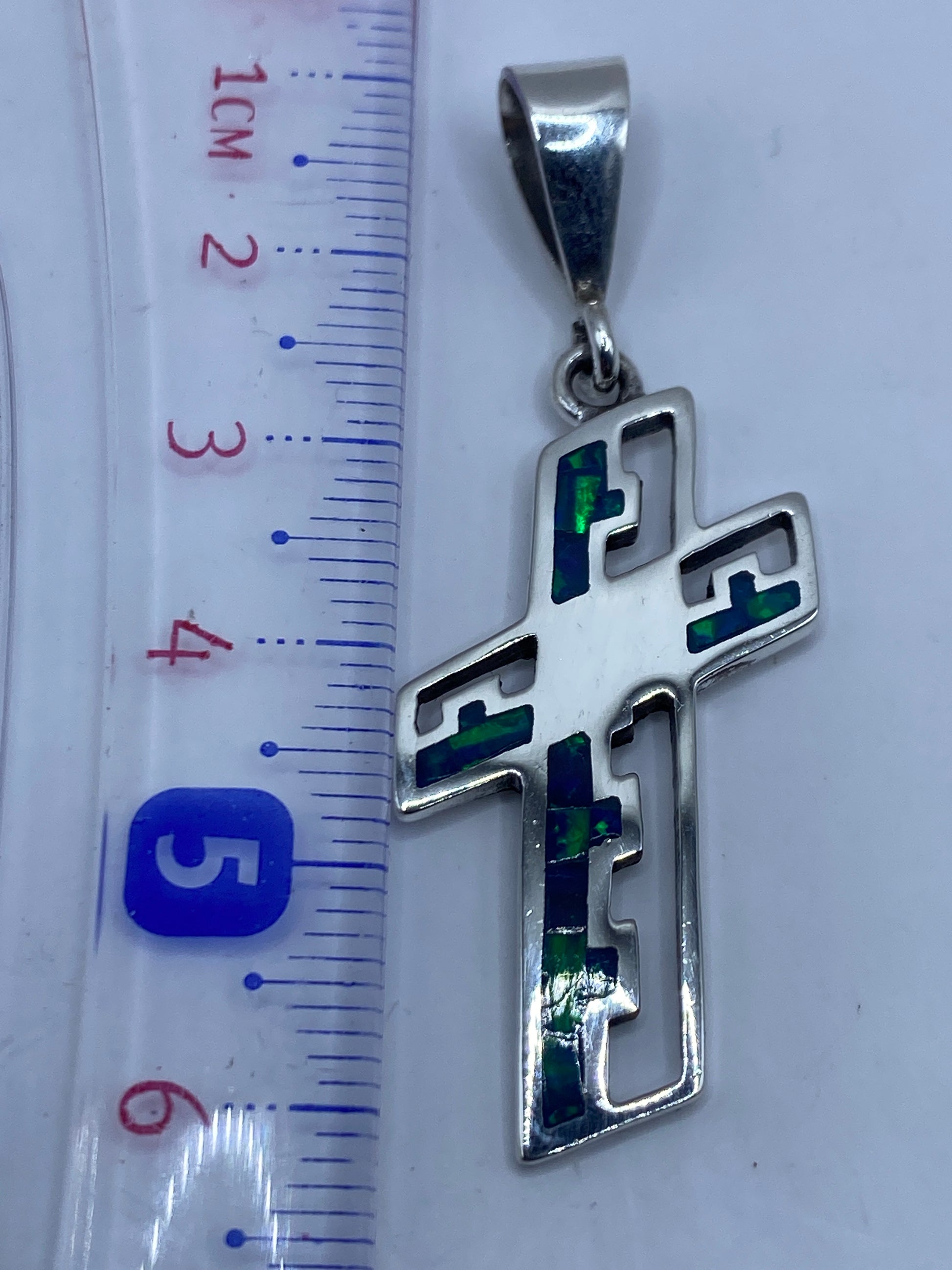 Dije cruz de 6.1 cm con Quinto .950 en reverso, sobre estuche blanco