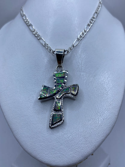 Detalle frontal de la cruz de plata mostrando los esmaltes de ópalo de fuego verde y naranja