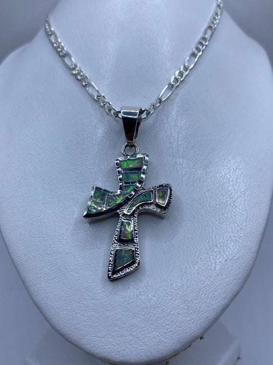 Detalle frontal de la cruz de plata mostrando los esmaltes de ópalo de fuego verde y naranja