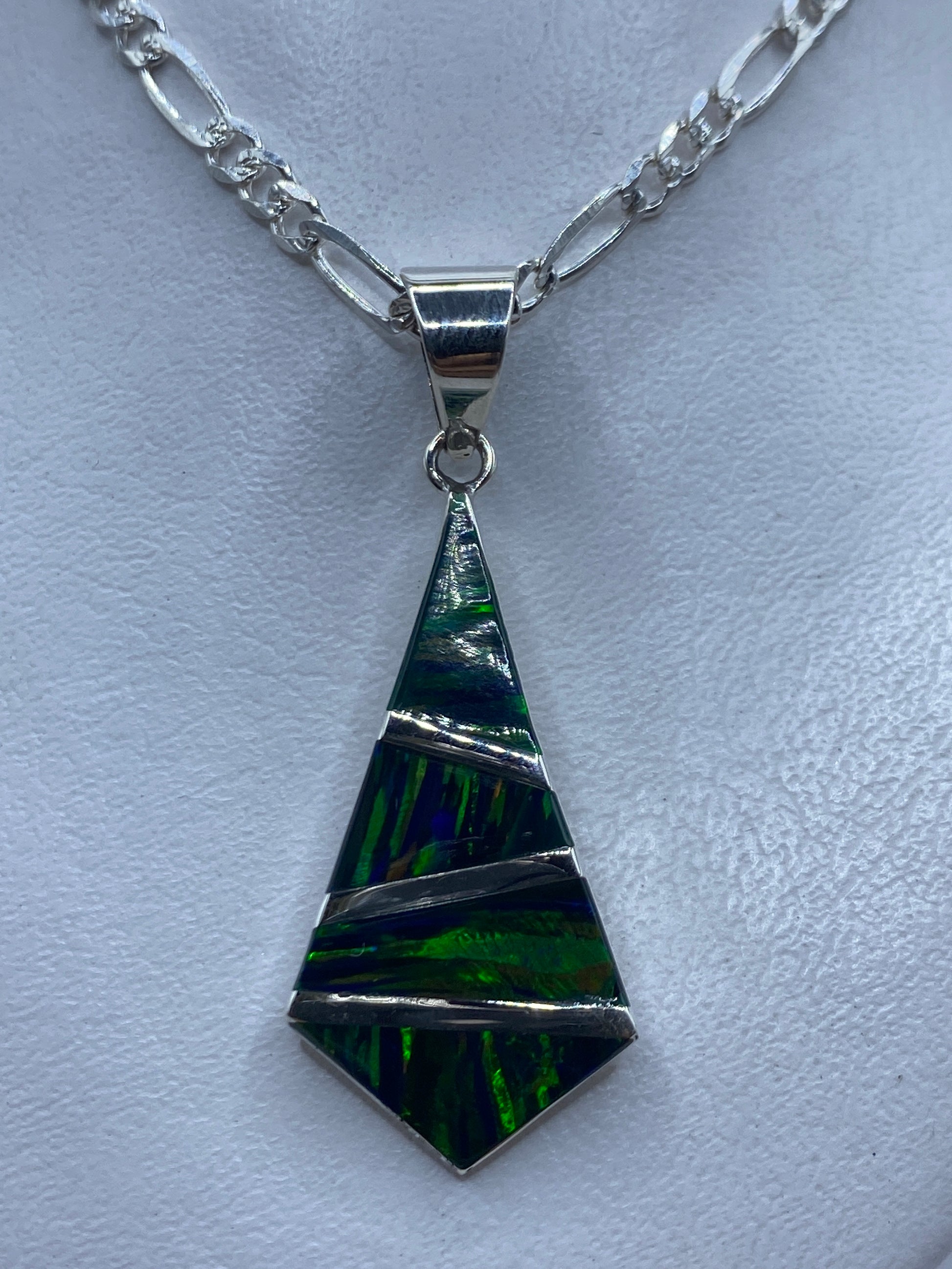 Dije tetraédrico de plata .950 con ópalo de fuego verde sobre cadena figaro en la piel