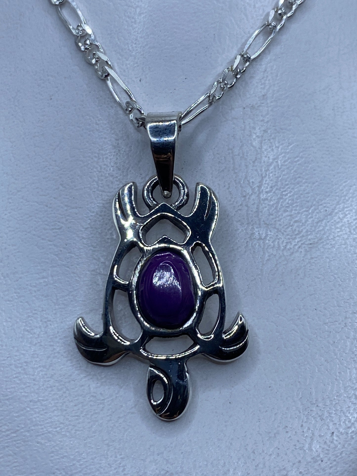 Dije prehispánico de plata .950 con piedra morada engastada, colgando de una cadena plateada