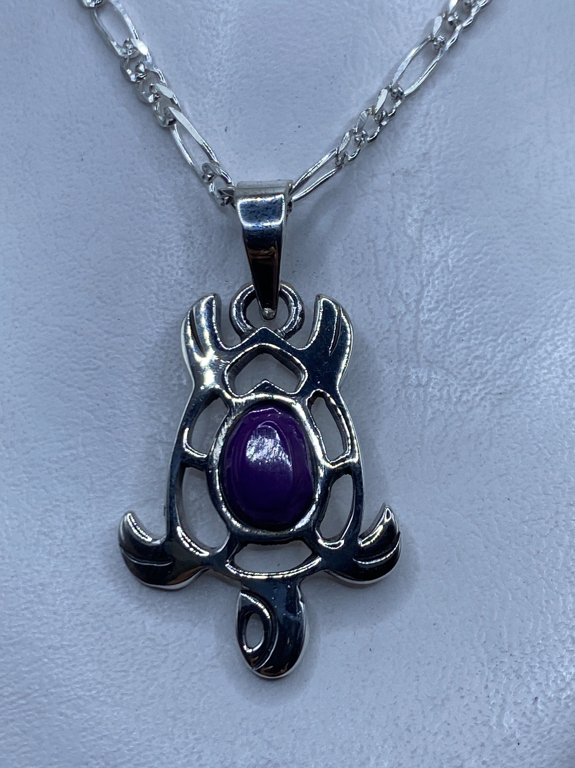 Dije prehispánico de plata .950 con piedra morada engastada, colgando de una cadena plateada