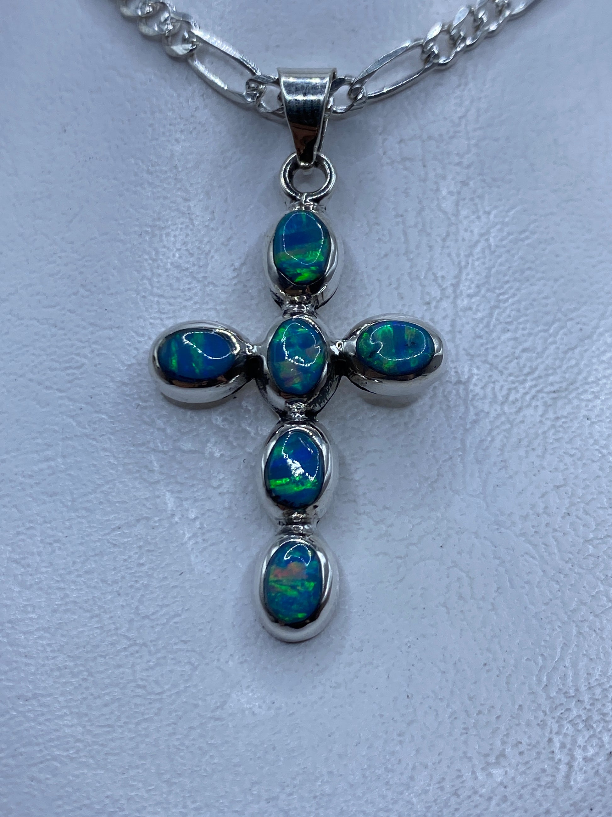 Dije cruz de plata .950 con ópalo de fuego azul cielo engastado, colgando de cadena