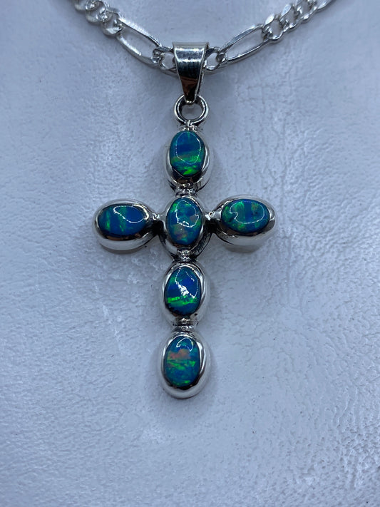 Dije cruz de plata .950 con ópalo de fuego azul cielo engastado, colgando de cadena
