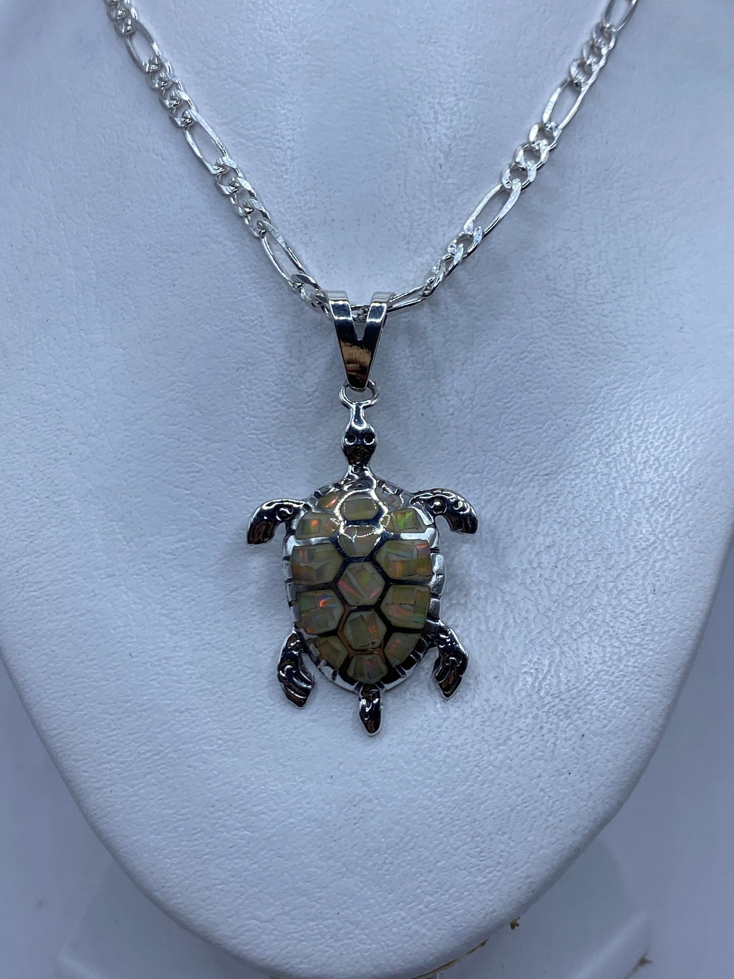 Tortuga marina de plata colgando de una cadena Figaro, sobre piel