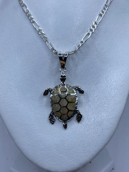 Tortuga marina de plata colgando de una cadena Figaro, sobre piel
