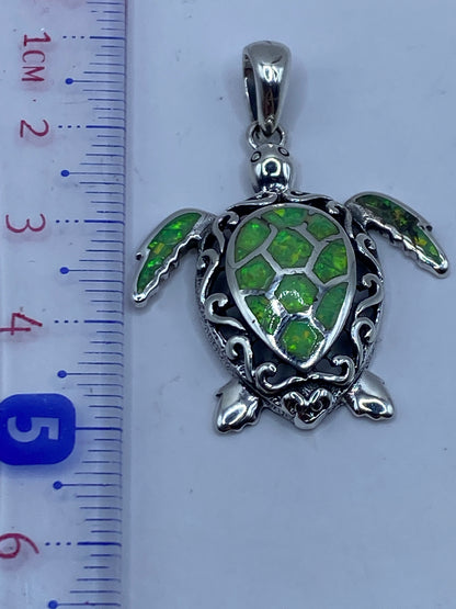 Dije tortuga marina medido a lado de regla, mostrando 4.7 cm de largo