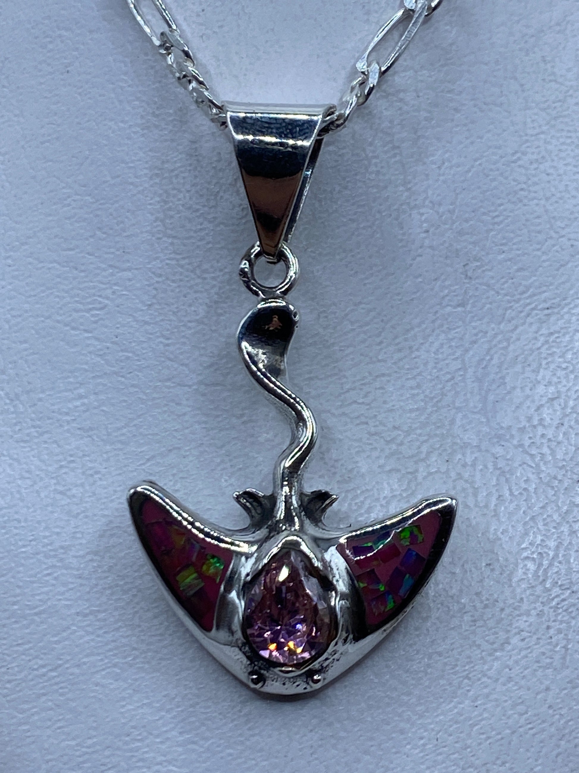 Dije de plata con ópalo de fuego rosa y alas, colgando de cadena plateada