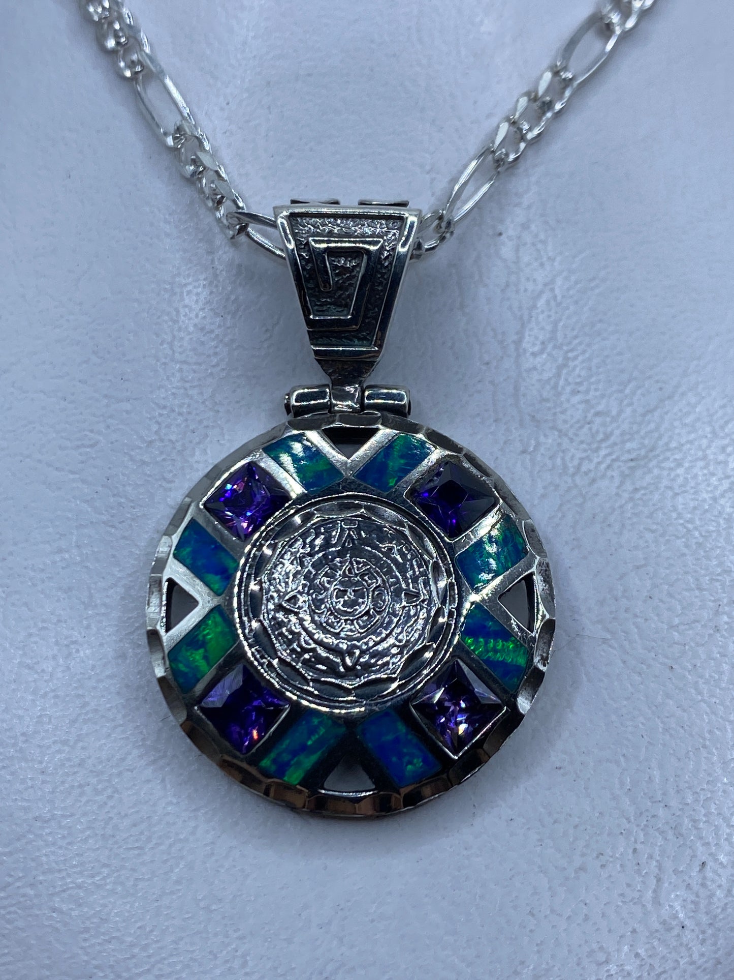 Dije circular de plata .950 con opalo de fuego azul y relieve prehispanico, colgando de cadena