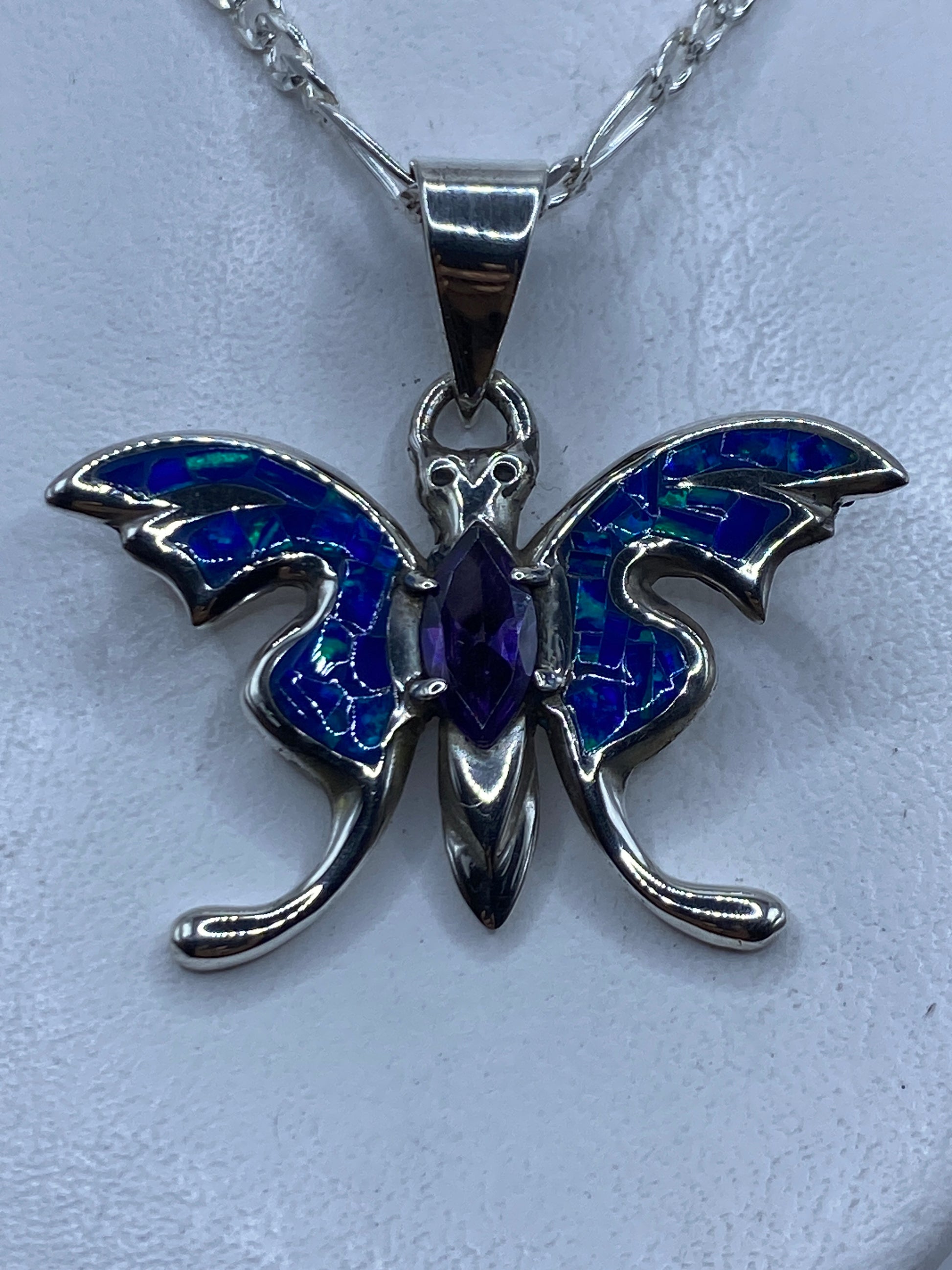 Dije de plata ópalo de fuego azul colgando de cadena plateada contra el pecho