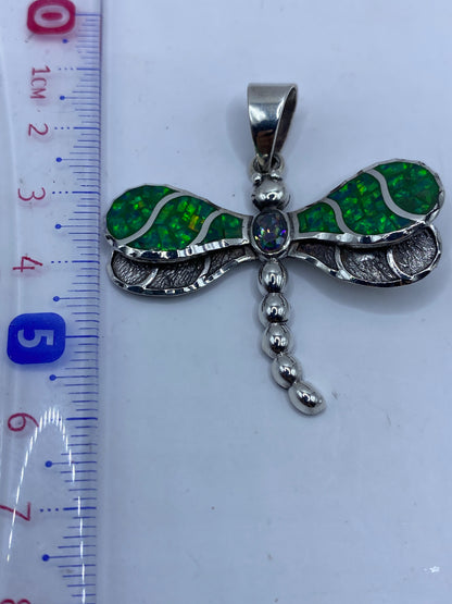 Dije libélula junto a regla mostrando largo de 5.6 cm
