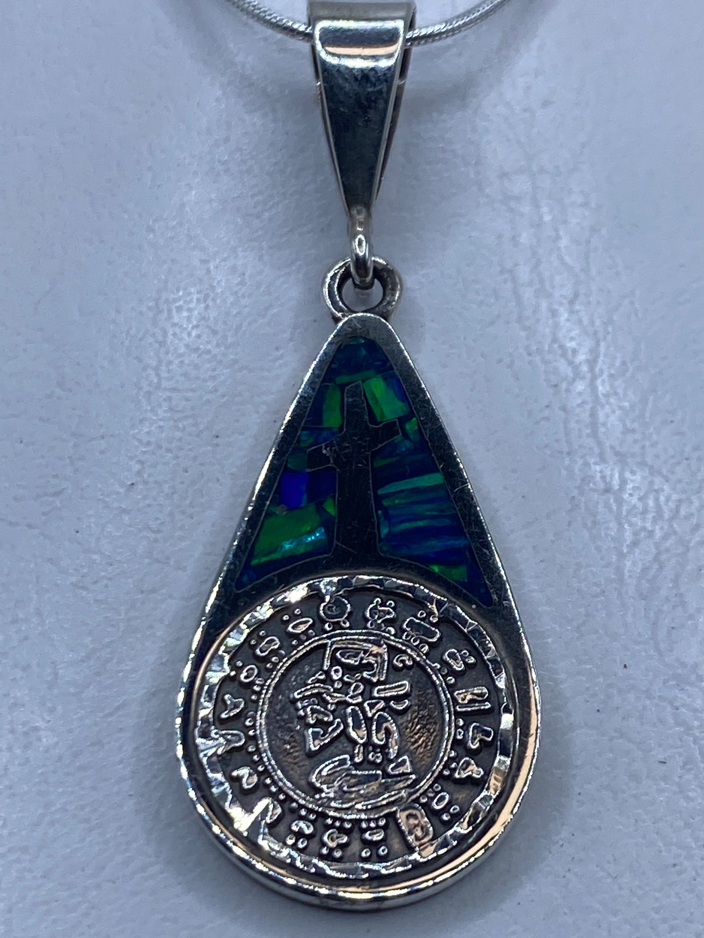 Dije de plata .950 con cruz y ópalo de fuego azul incluye cadena, colgando de un collar