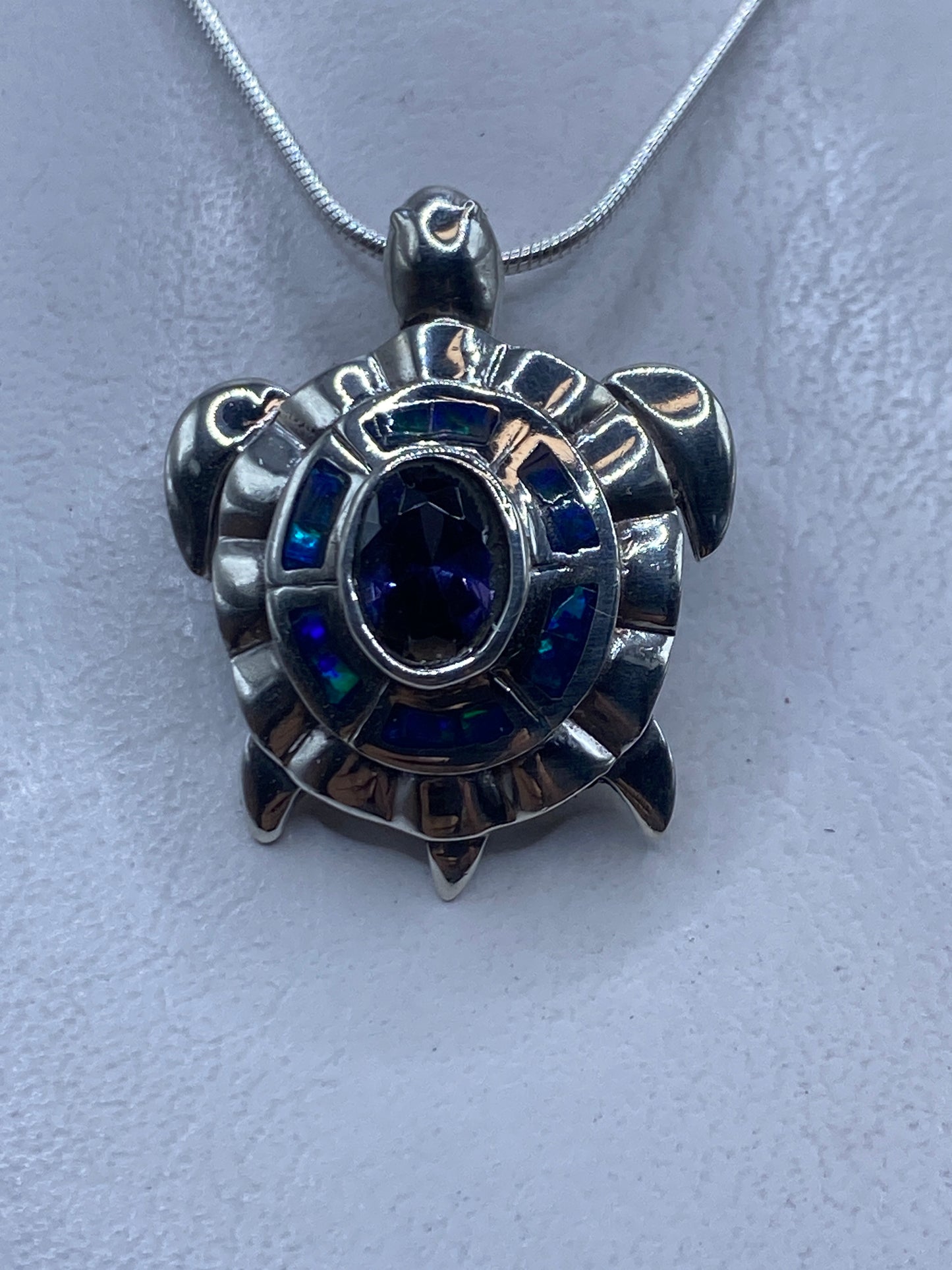 Dije de plata con ópalo de fuego azul engastado, colgando de cadena de plata