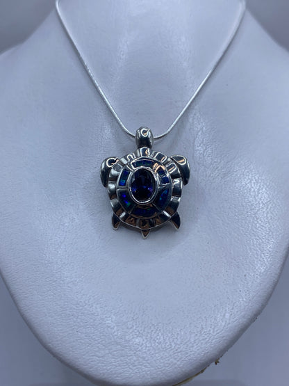 Vista frontal del dije de 3.5 cm con ópalo azul y patrones de relieve en plata