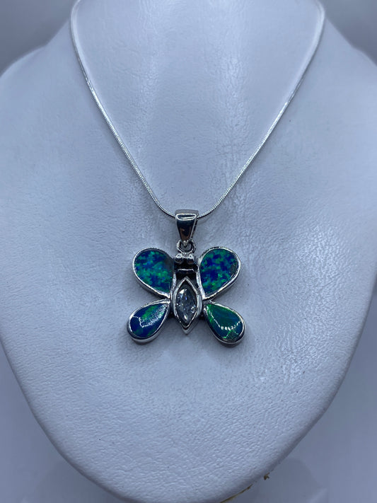 Detalle del dije mariposa mostrando el juego de color azul y verde del ópalo de fuego