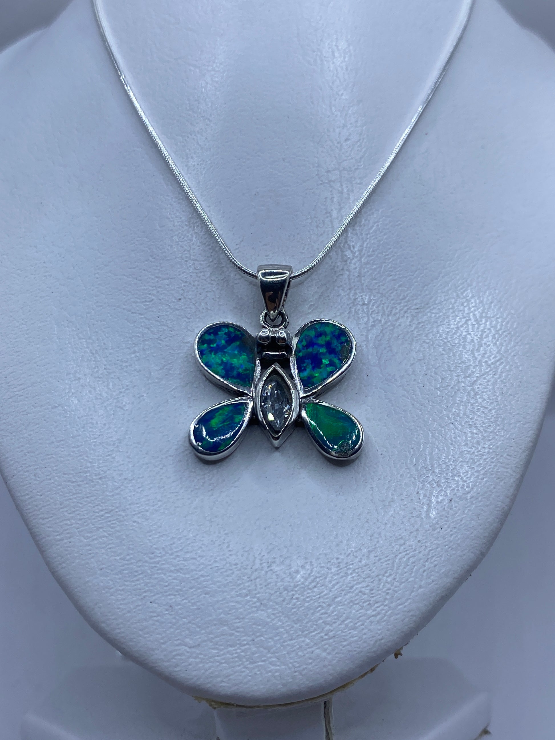 Mariposa de plata con granulado en las alas y ópalo azul en el centro, portada sobre piel