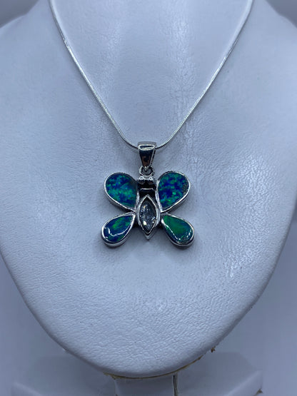 Mariposa de plata con granulado en las alas y ópalo azul en el centro, portada sobre piel