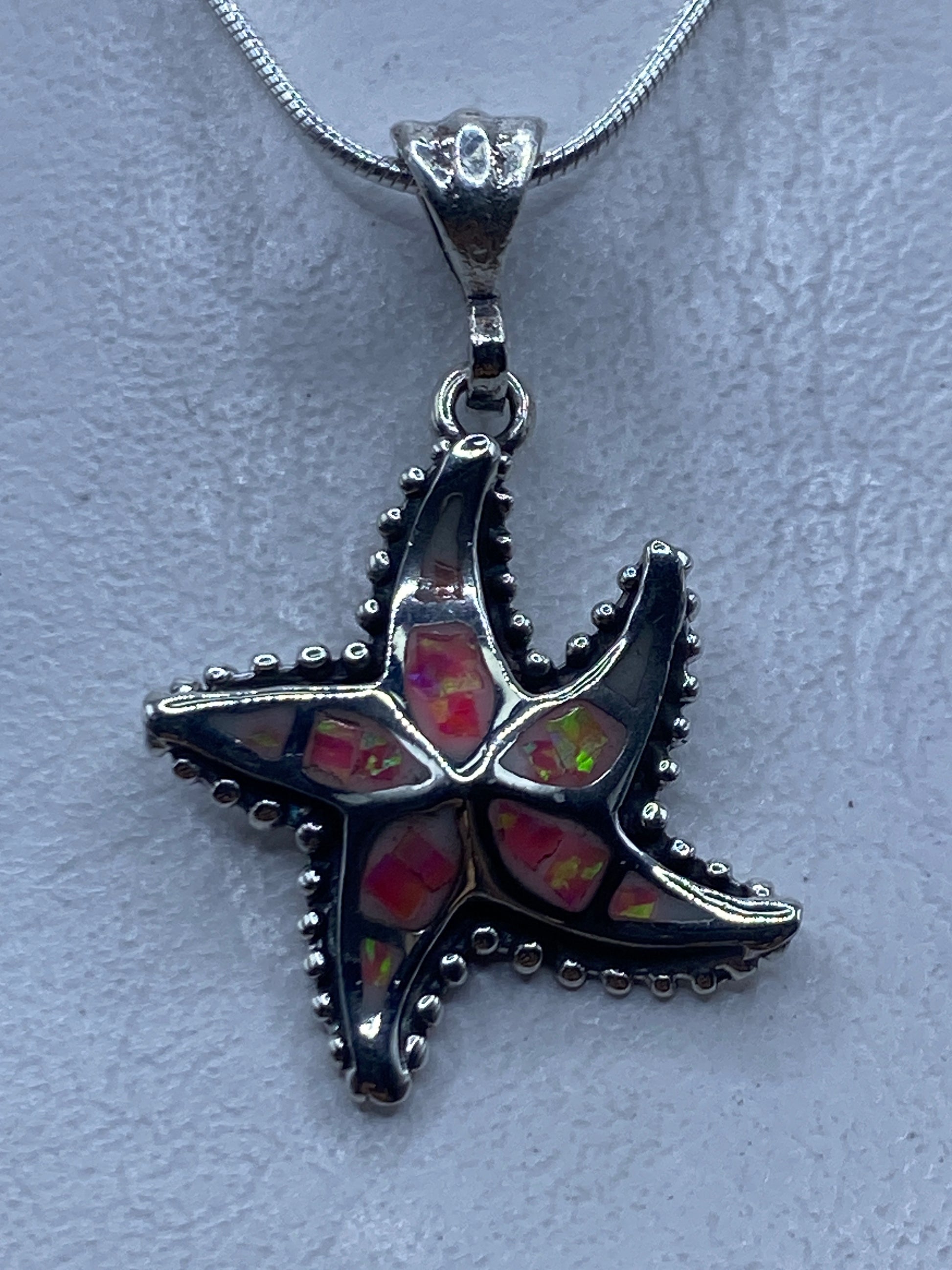 Dije estrella de mar en plata .950 con ópalo de fuego rosa, colgado en cadena de serpentina