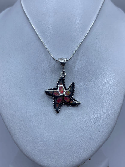 Detalle del engaste artesanal de ópalo de fuego rosa en las puntas de la estrella de plata