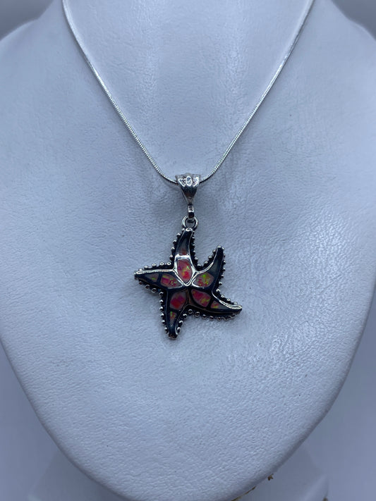 Detalle del engaste artesanal de ópalo de fuego rosa en las puntas de la estrella de plata