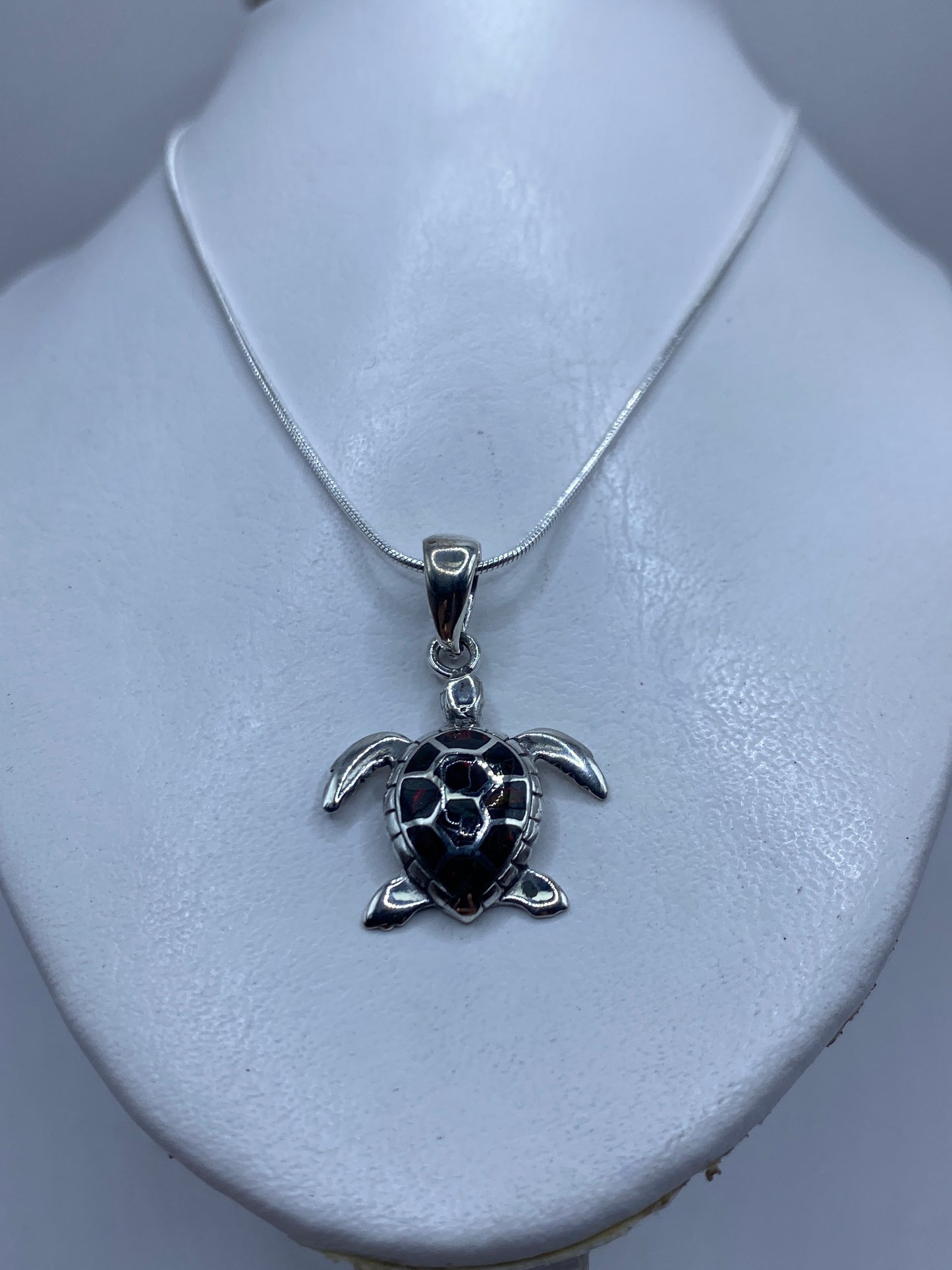 Dije de tortuga de 3.9 cm de largo mostrado junto a una regla para escala