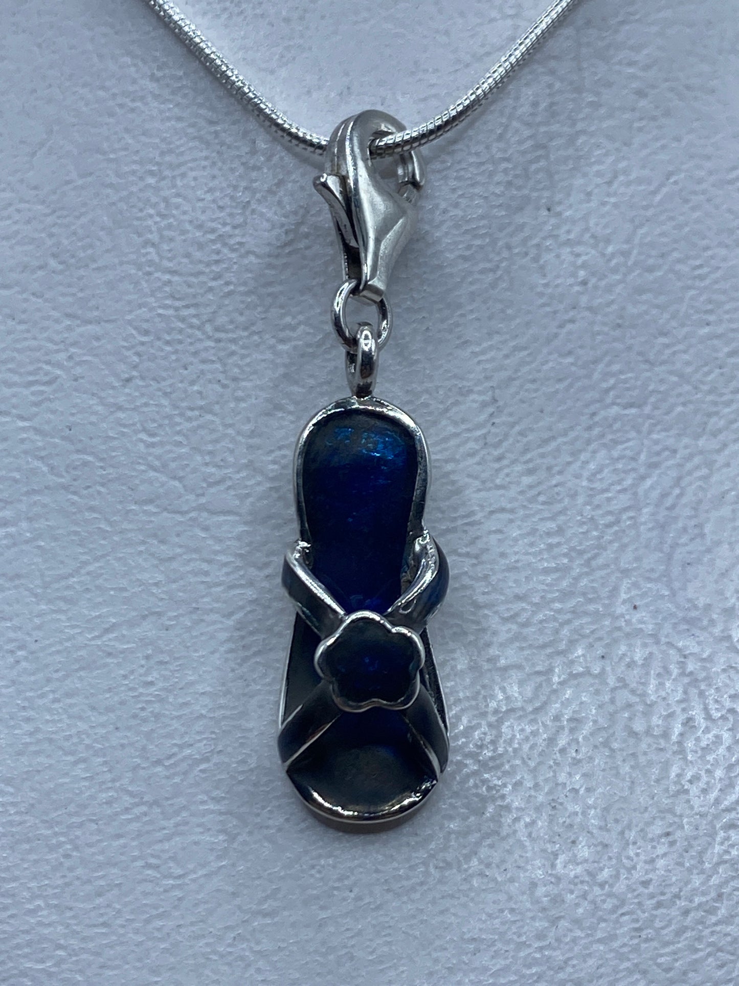Dije de plata .925 con piedra azul engastada, colgando de cadena plateada